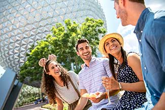 Three young people eating and drinking with Spaceship Earth in the backgroiund