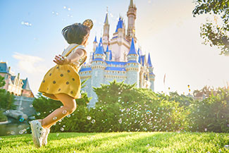 View of a young girl skipping and blowing bubbles in front of Cinderella Castle