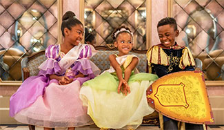 View of three smiling kids dressed up as princes and princesses