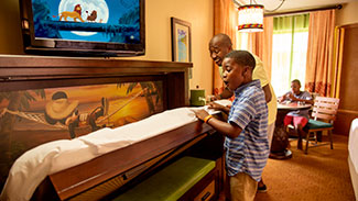 A father and son open the pull-down bed in a Caribbean Beach Resort bedroom