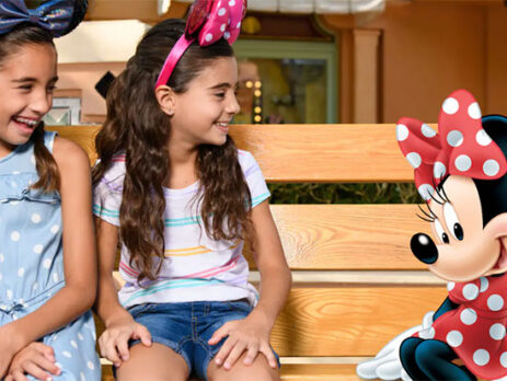 A MemoryMaker photo of two cute little girls sitting next to Minnie Mouse