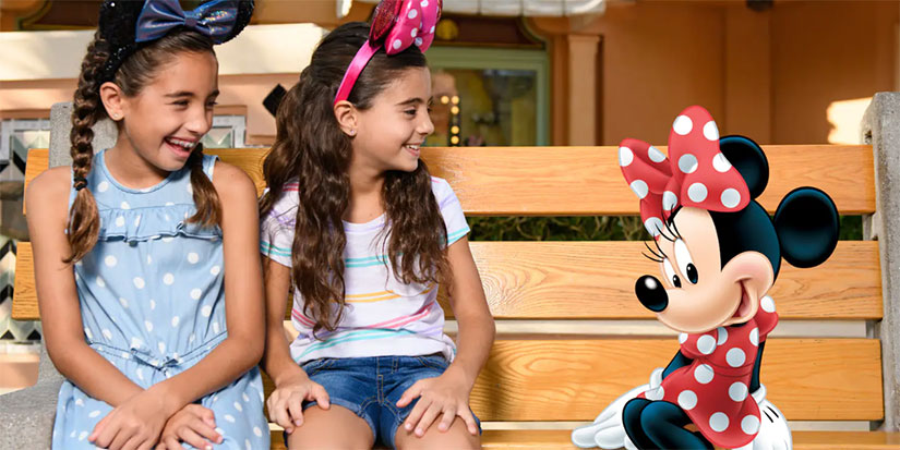 A MemoryMaker photo of two cute little girls sitting next to Minnie Mouse