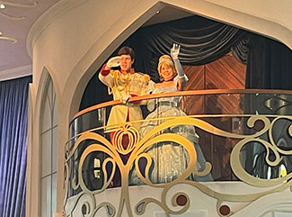 Cinderella and Prince Charming waving from the balcony in the Atrium aboard the Disney Wish