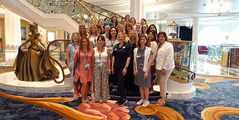 Photo of Magical Vacations Travel agents posing on the Grand Staircase aboard the Disney Wish cruise ship