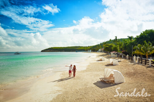 couple walking along the beach at a Sandals resort
