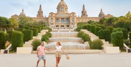 Couple holding hands in fron of fountain in Barcelona