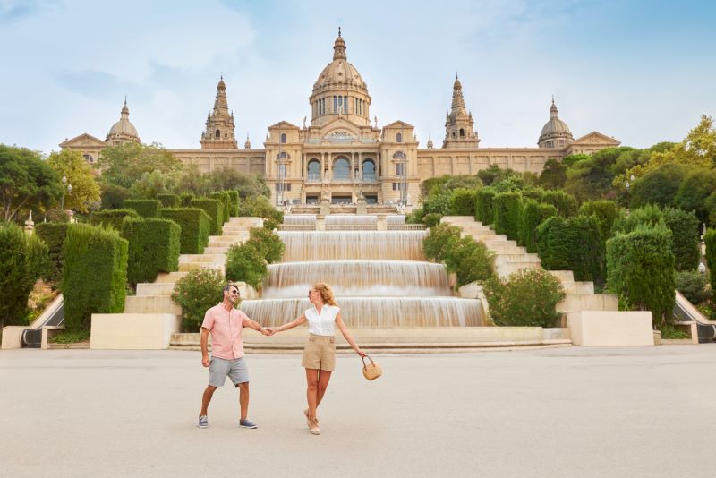 Couple holding hands in fron of fountain in Barcelona